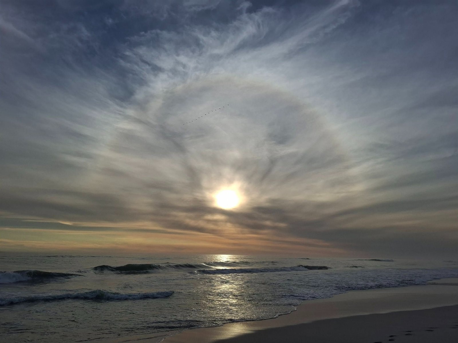 The sun behind thin cloud over the sea